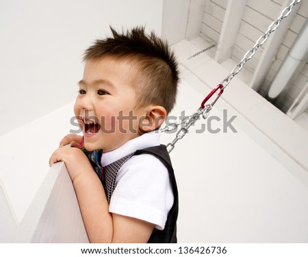 Fun loving young male child playing swinging smiling happy healthy boy