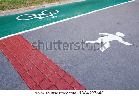 The symbol on the street in the park Bicycle lane on a green background And people picture are running or walking on the concrete road. Track for exercise