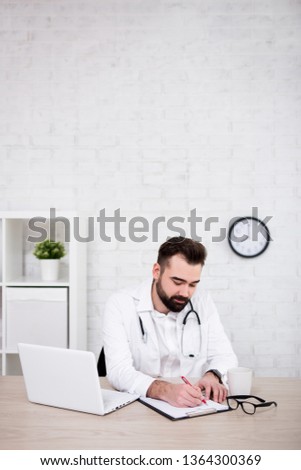 handsome man doctor working in office - copy space over white brick wall background