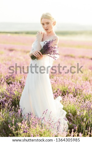 Wonderful portrait of girl in light dress in lavender field on golden sunset