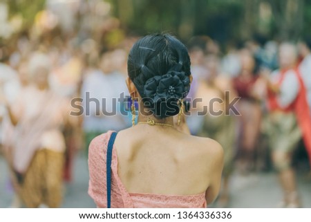 Back view of female in Thai dress  take a photo of a Thai dance parade in Songkran festival in Kanchanaburi Thailand.