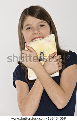 Little girl holding a copybook biting teeth