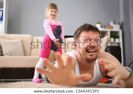 Cute little girl hold her father leg as proof of winning battle game portrait