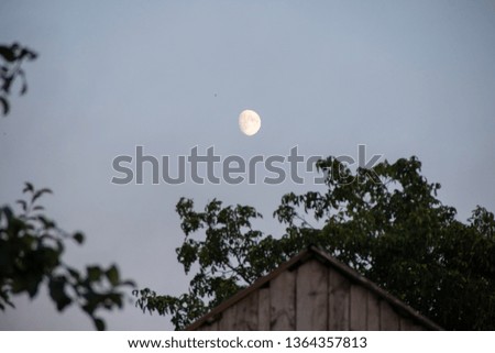 A young moon in the sky above an old country house