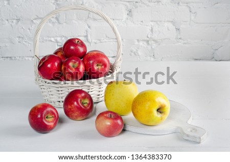 Red and yellow apples in basket on  white table against the background of  white wall. Сopy space.