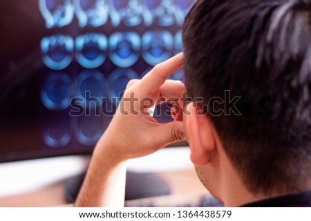 Doctor radiologist in hospital looking at mri x-ray scan of brain, head and skull ct scanning image on digital computer screen. Selective focus photography