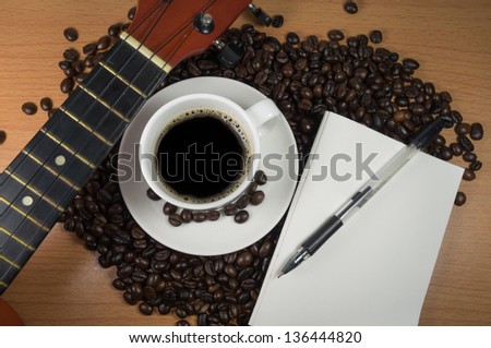 Espresso coffee in white cup with guitar and paper