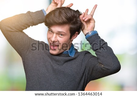 Young handsome elegant man over isolated background Posing funny and crazy with fingers on head as bunny ears, smiling cheerful