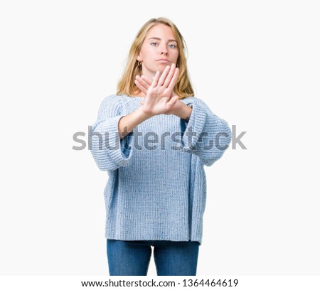 Beautiful young woman wearing blue sweater over isolated background Rejection expression crossing arms and palms doing negative sign, angry face