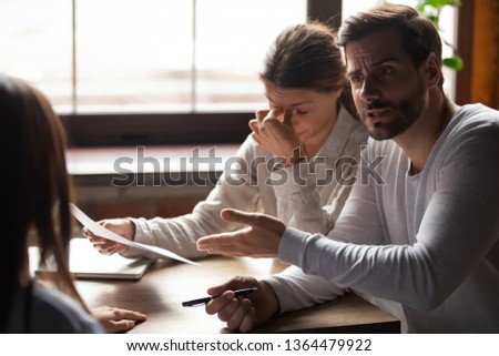Diverse millennial people sitting at table in office indignant man accusing incompetent unqualified woman colleague pointing on financial report with mistakes, lack of education and knowledge concept Royalty-Free Stock Photo #1364479922