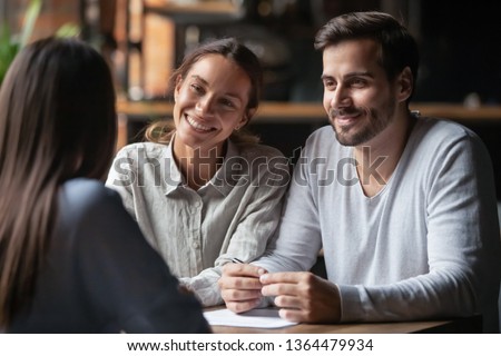 Biracial woman caucasian man listen vacancy candidate sitting together at table at job interview. Diverse couple communicating with real estate agent, successful meeting ready to sign contract concept