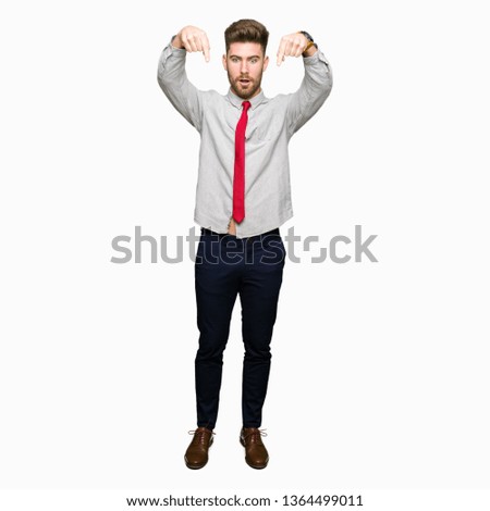Young handsome business man Pointing down with fingers showing advertisement, surprised face and open mouth