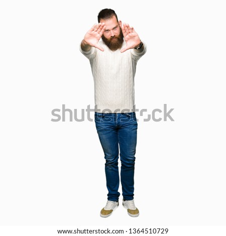 Young hipster man wearing winter sweater Smiling doing frame using hands palms and fingers, camera perspective