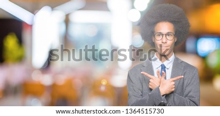Young african american business man with afro hair wearing glasses Pointing to both sides with fingers, different direction disagree