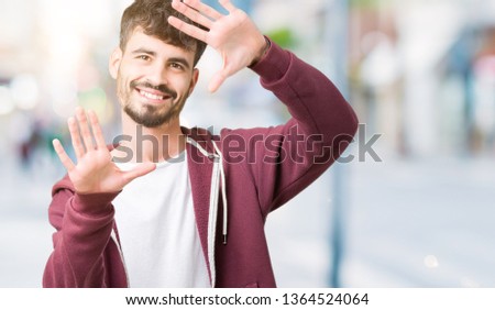 Young handsome man over isolated background Smiling doing frame using hands palms and fingers, camera perspective