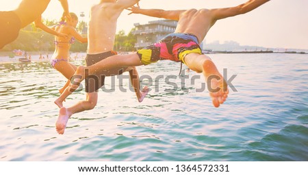 Group of happy crazy people having fun jumping in the sea water from boat. Friends jump in mid air on sunny day summer pool party at diving holiday. Travel vacation, friendship, youth holiday concept. Royalty-Free Stock Photo #1364572331