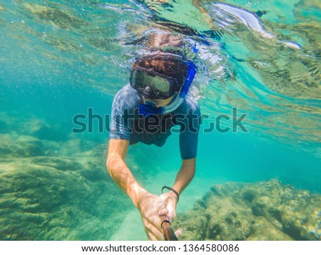 young men snorkeling exploring underwater coral reef landscape background in the deep blue ocean with colorful fish and marine life