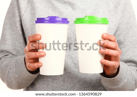 Human hand holds a blank paper Coffee cup with plastic cap. Concept of tea or coffee to go in a disposable mug. Mockup with copy space and place for text or logo. Isolated on a white background