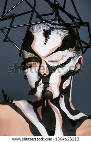 Female model with creative abstract makeup in futuristic hat.