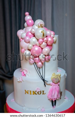 Two-storey white cake with the image of a girl with colorful balloons on the background of curtains. 