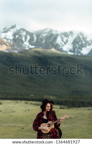 Girl with a guitar in the mountains.