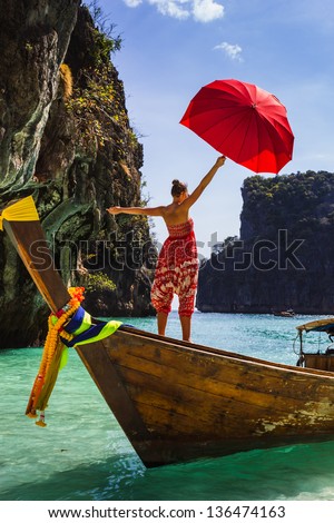Girl with a red umbrella on a boat at a resort in Thailand