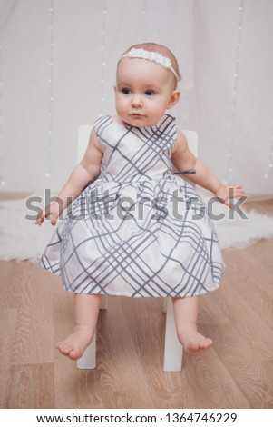 a little girl in a dress sits on a chair and smiles