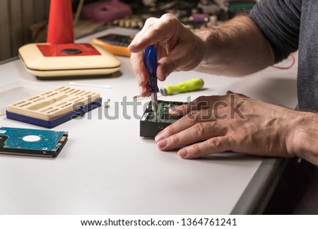 electronic engineer repairs computer hard drive. technologist with a screwdriver disassembles hdd