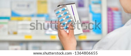 Pharmacist holding medicine box and capsule pack at the pharmacy drugstore Royalty-Free Stock Photo #1364806655