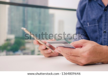 Online payment, Closeup young man hands holding a credit card and using smart phone for online shopping or reporting lost card is city outside background, New generation gadget
