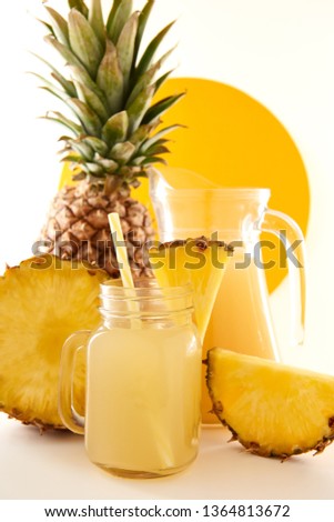 Jug and glass of pineapple juice with fruits on white background. Sweet and tasty yellow is a useful vitamin. Summer composition