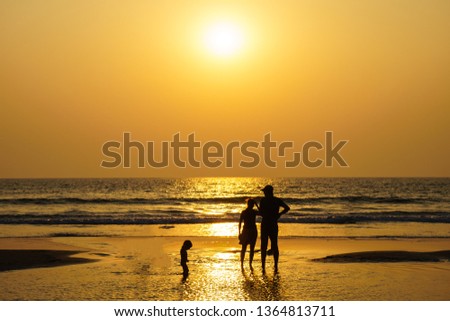 Silhouettes of family members on the beach at the amazing orange sunset