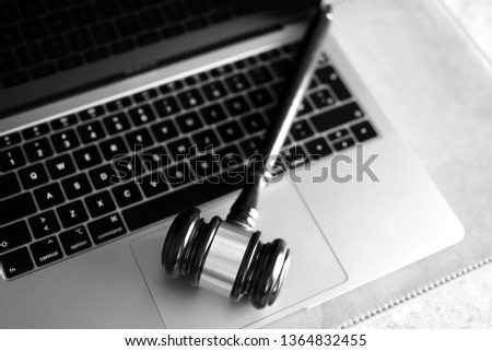 Judge gavel on laptop computer keyboard, black and white. Concept of online auction, cyber crime, law system.
