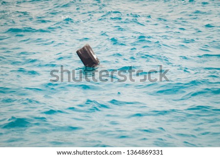 Black plastic canister floats in the sea. Household waste, concept of lack of respect for the environment