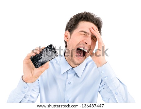 Handsome angry businessman showing broken smartphone with crashed screen. Isolated on white background.