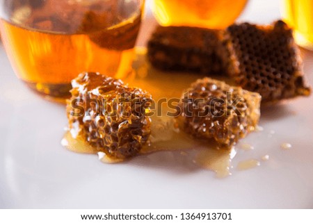 Honey in jar with honey dipper on wooden background.
