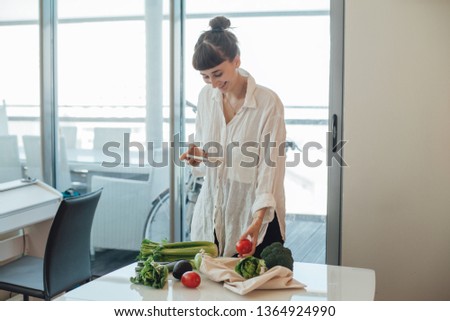 Happy healthy girl doing photo of fresh vegetables that she bought on a local farm market to post it in her social media and tell friends about sustainable shopping and zero waste food shopping