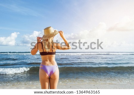 Girl in a hat standing on the beach and looking at the ocean. copy space on the right