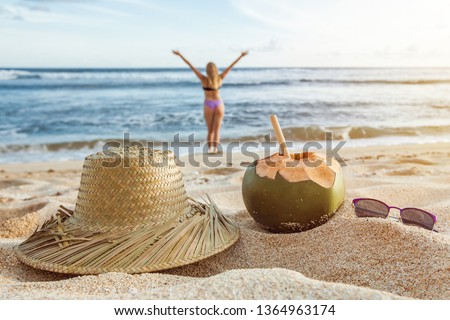A young coconut with a solvin hat and sunglasses lies on the beach on the sand. Summer background. Summer holiday concept