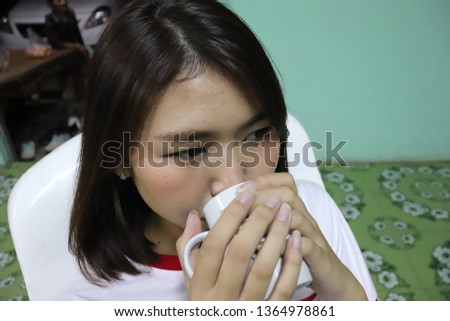 Young asian woman with short hair is drinking something