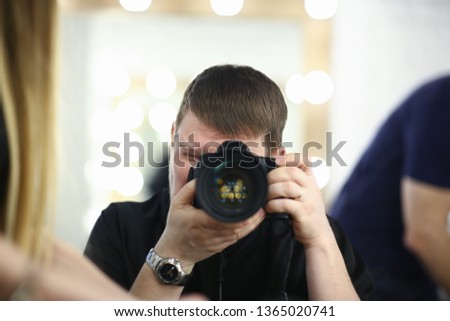 A male photographer holds camera in his hand concept. The self-portrait is reflected in the mirror.