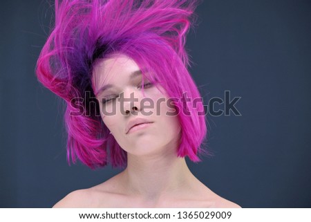 Concept Portrait of a punk girl, young woman with chic purple hair color in studio close up on a colorful background with fluttering hair. Short hairstyle, fashion haircut.