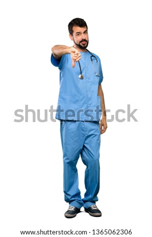 Full-length shot of Surgeon doctor man showing thumb down with negative expression over isolated white background