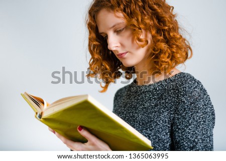 beautiful curly woman reading a book, isolated on gray background