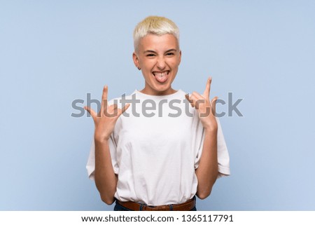 Teenager girl with white short hair over blue wall making rock gesture