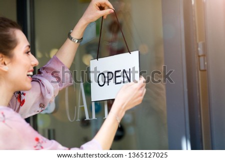 Woman holding open sign in cafe