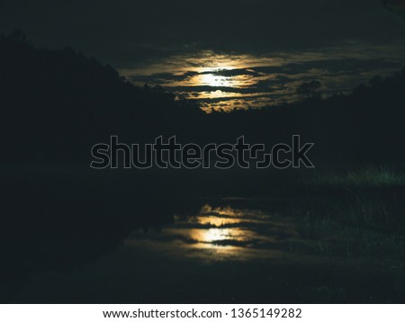 Landscape at night time background .Cloud hind the moon reflex on the river.