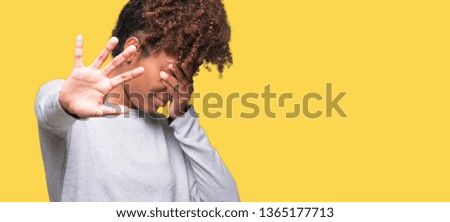 Beautiful young african american woman over isolated background covering eyes with hands and doing stop gesture with sad and fear expression. Embarrassed and negative concept.