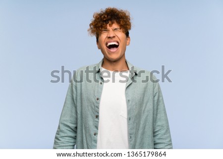Young african american man over isolated blue wall shouting to the front with mouth wide open