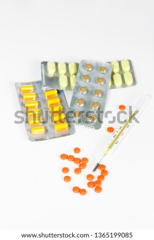 multi-colored yellow orange brown pills and a temperature thermometer on white background